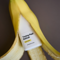 Dermathod Toning Peel Refiner nighttime treatment tube resting on a peeled banana, highlighting AHA and BHA exfoliating ingredients.