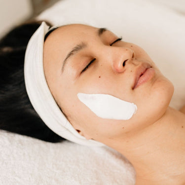 Woman receiving a professional facial treatment with brightening cream applied to her cheeks — Corthe Dermo Bright Toning Lumedic for radiant, even-toned skin