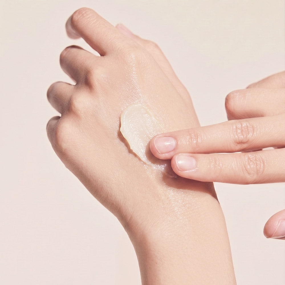 Close-up of Dermathod Toning Peel Refiner cream texture being smoothed onto the back of a hand against a soft beige background